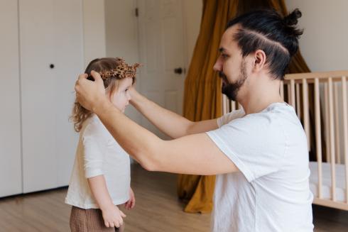 Mies asettelee lapsen päähän hiuskoristetta.
