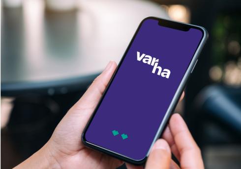 Henkilöllä on kädessään älypuhelin, jonka näytöllä näkyy Varhan logo. 