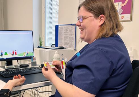 Kuvassa diabeteshoitaja työhuoneessaan. Tietokoneella hänen edessään on auki digihoitopolun ammattilaisnäkymä.
