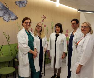Erikoislääkärit Johanna Hynninen, Jenni Söderlund, Titta Joutsiniemi, Tuukka Mettälä ja Marjut  Haataja. Taustalla seinä, jossa kukkia ja perhosia.