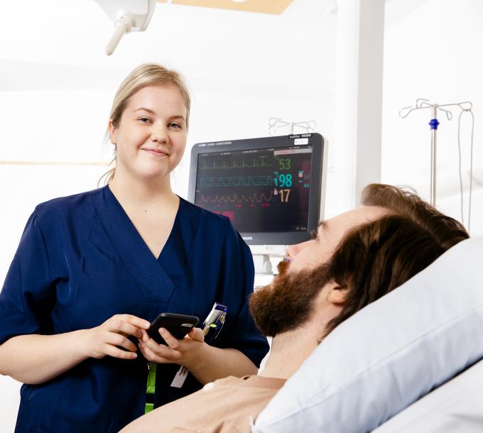 Sjuksköterskan ler mot patientens säng.