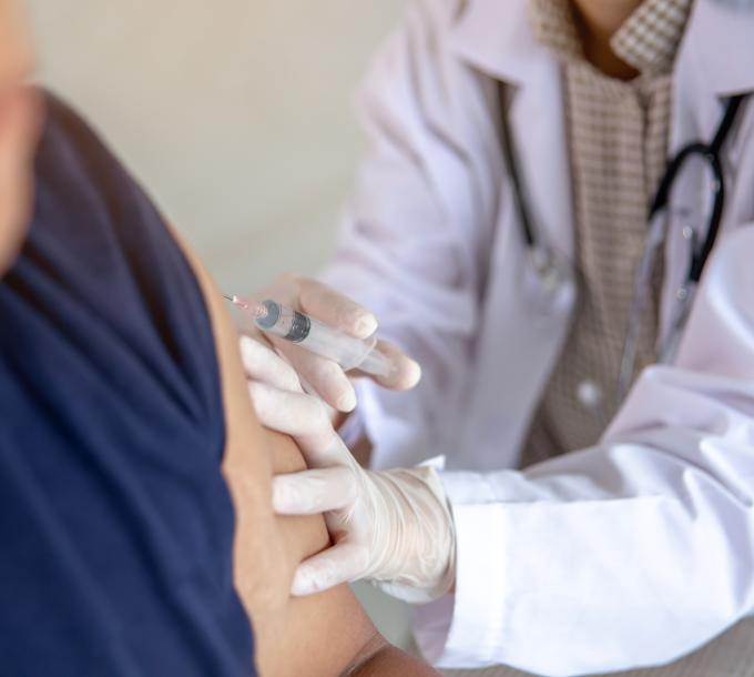 A healthcare professional injects a vaccination into a client's upper arm.