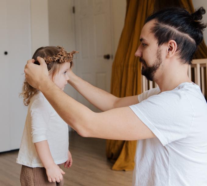 Mies asettelee lapsen päähän hiuskoristetta.