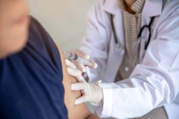 En vårdpersonal injicerar en vaccination i en klients överarm.