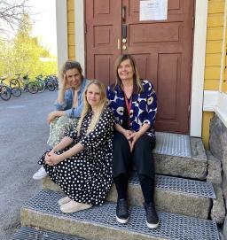 Juuia Salminen ja Vähä-Heikkilän koulun kaksi opettajaa istun puisen rakennuksen portailla.